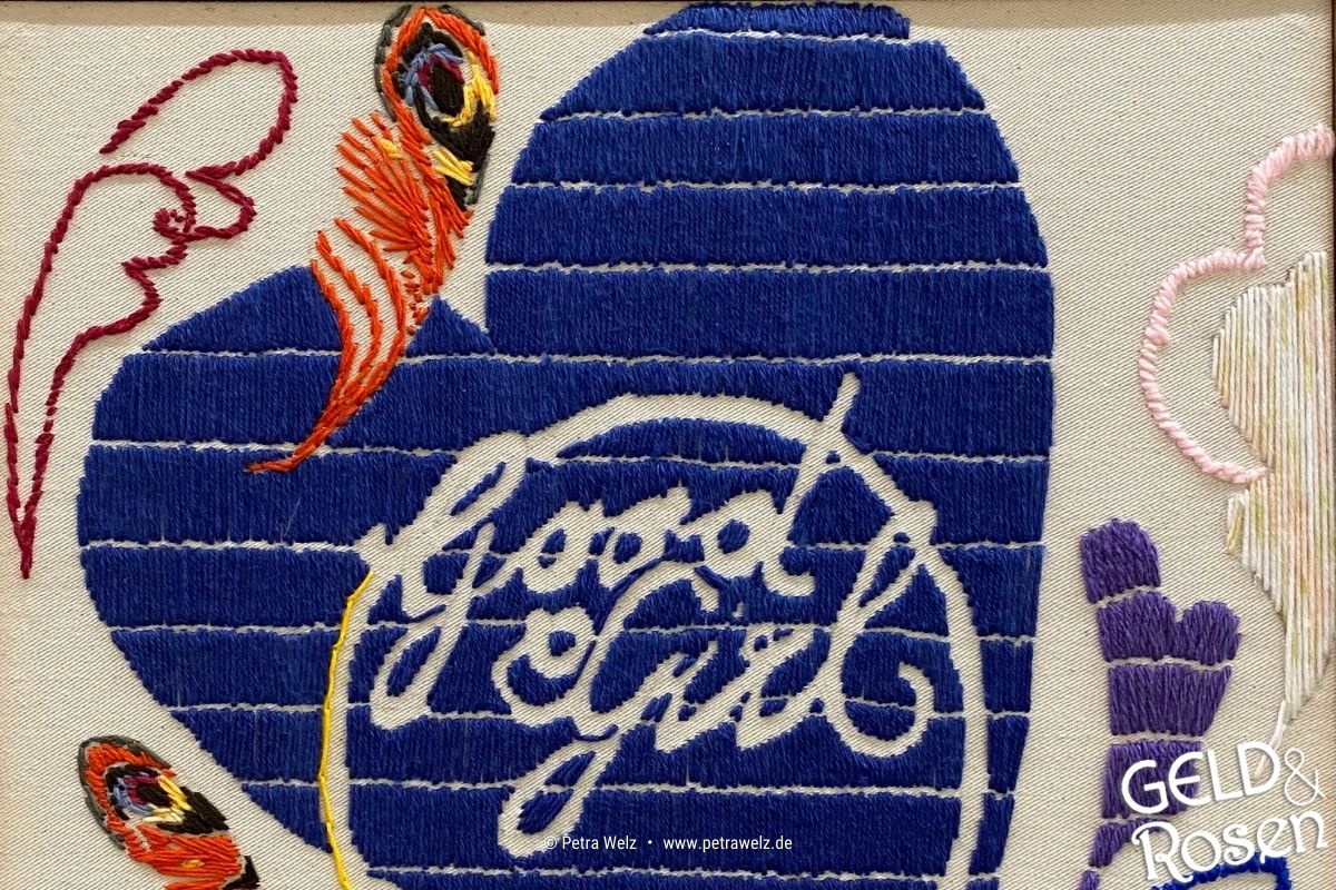 Das Bild zeigt ein besticktes Handtuch mit einem blauen Herz und dem Schriftzug "Good Girl" als Bildmetapher für die eigene Definition von Erfolg (Photocredit: Petra Welz, Geld & Rosen, Düsseldorf)
