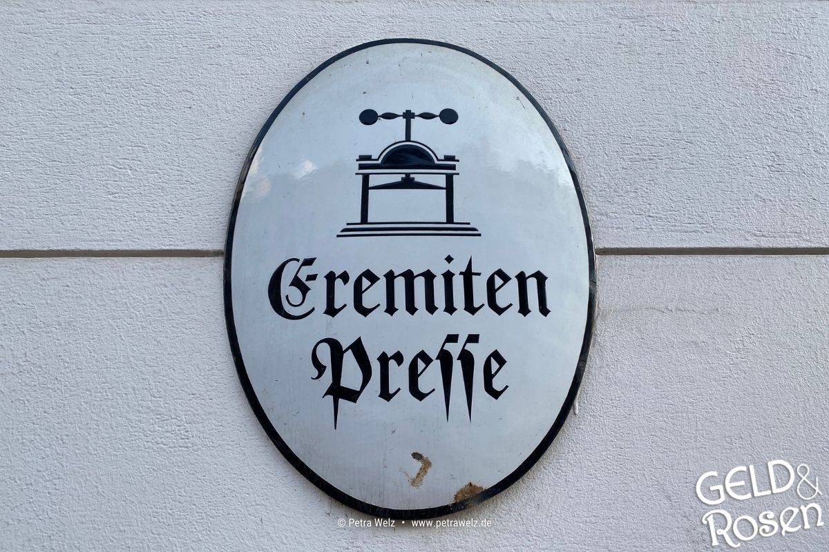 Das Bild zeigt ein antikes Emaille-Schild mit der Aufschrift "Eremiten-Presse" als Bildmetapher für überholte Ansätze im Geschäftsleben, heute: Verweigerung von Einsatz der KI im Sozialwesen und der Gesundheitswirtschaft (Bild: eigenes Material Petra Welz, Geld & Rosen, Düsseldorf).